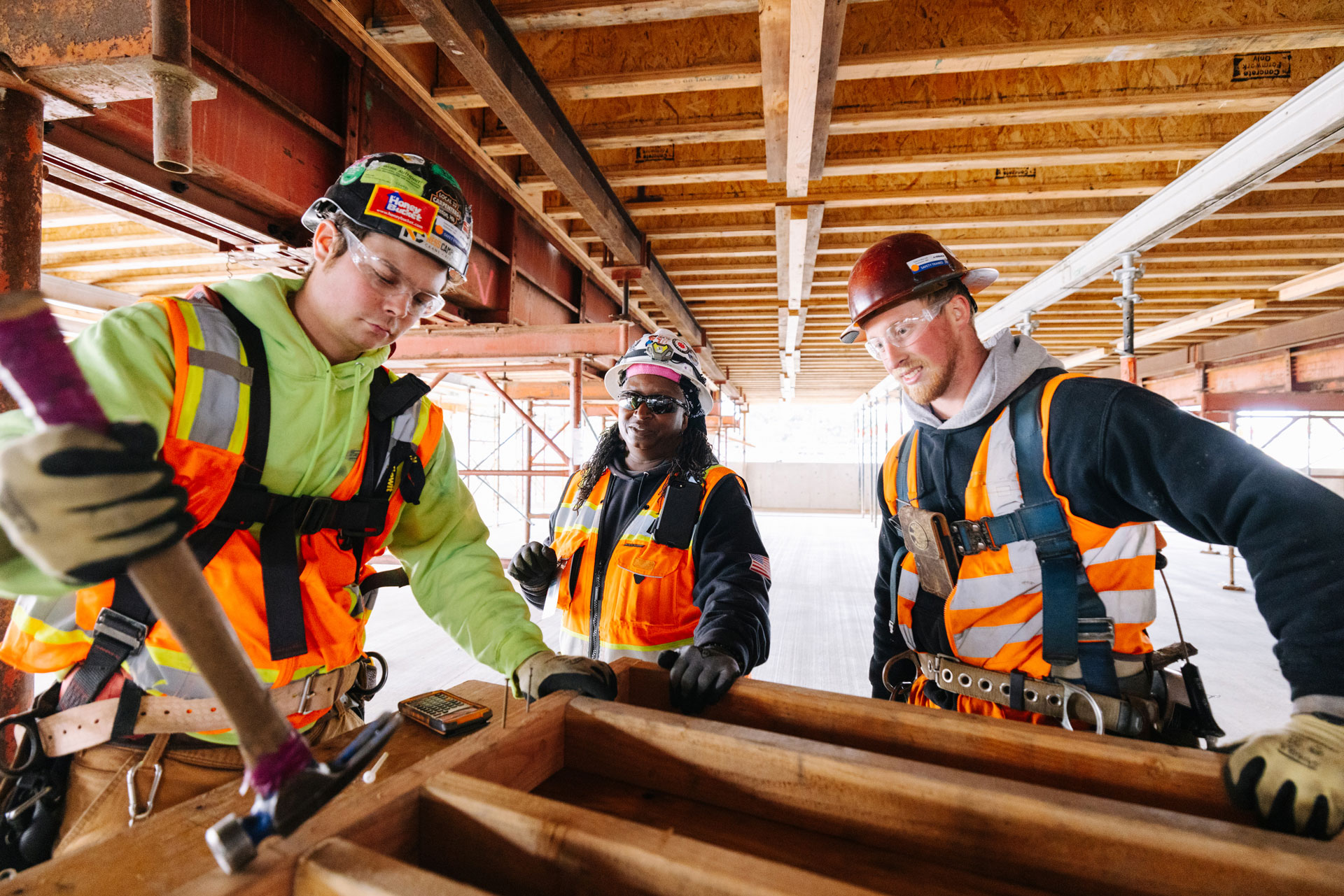 Se muestra a tres trabajadores de la construcción con equipo de seguridad y herramientas construyendo el edificio de la Extensión de Link a Federal Way.