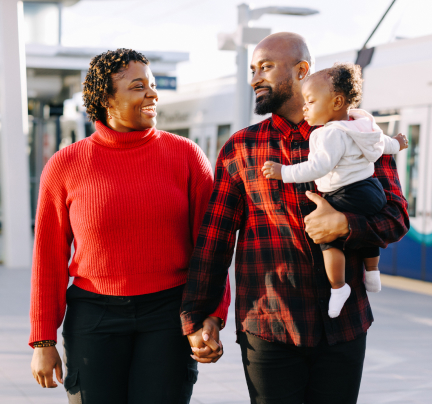 A family smiles at each other as they walk through a Link light rail station.